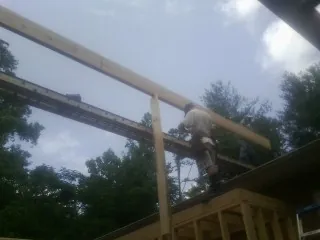 Carpenter setting a ridge beam over a new addition frame — Ice Dam Removal by Roofing Brothers in Beech Creek