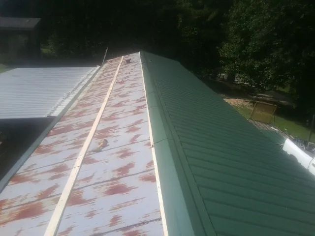 Old rusted panels beside newly installed green metal roofing — Wind Damage Roof Repair by Roofing Brothers in Beech Creek