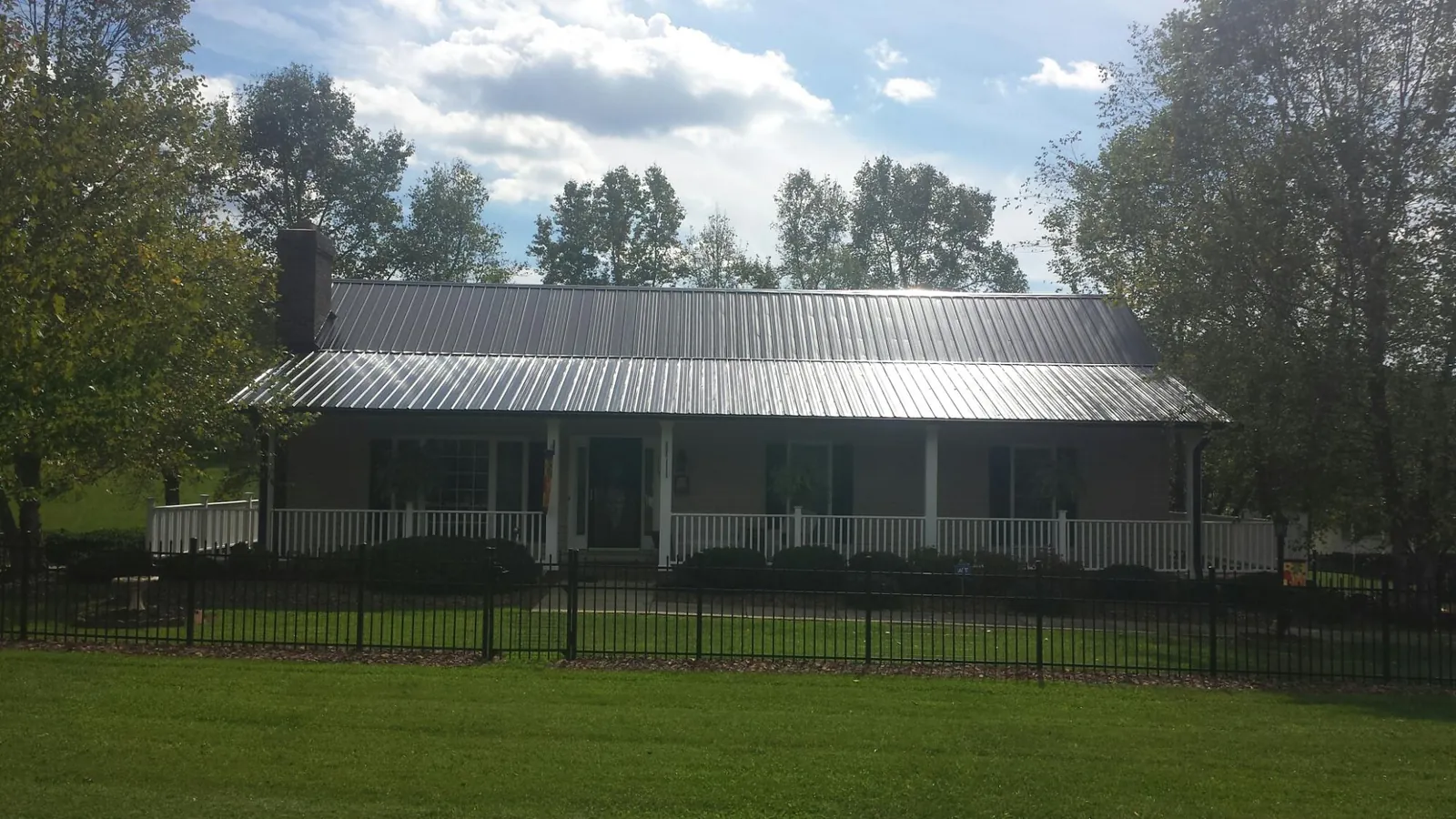 Gray metal roof on a brick ranch with a full width front porch — Gutter Guard Installation work by our crew in Beech Creek