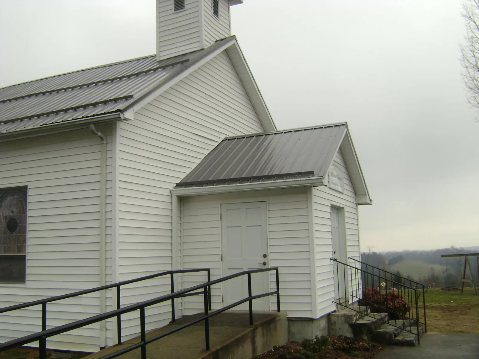 Gray metal roof on a white clapboard church with a steeple in Beech Creek